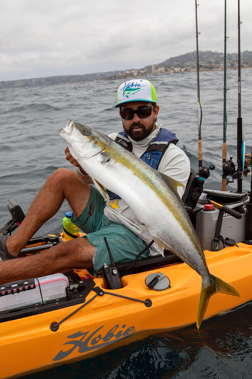 Howie Strech holds up a yellowtail caught by stickbait from a kayak