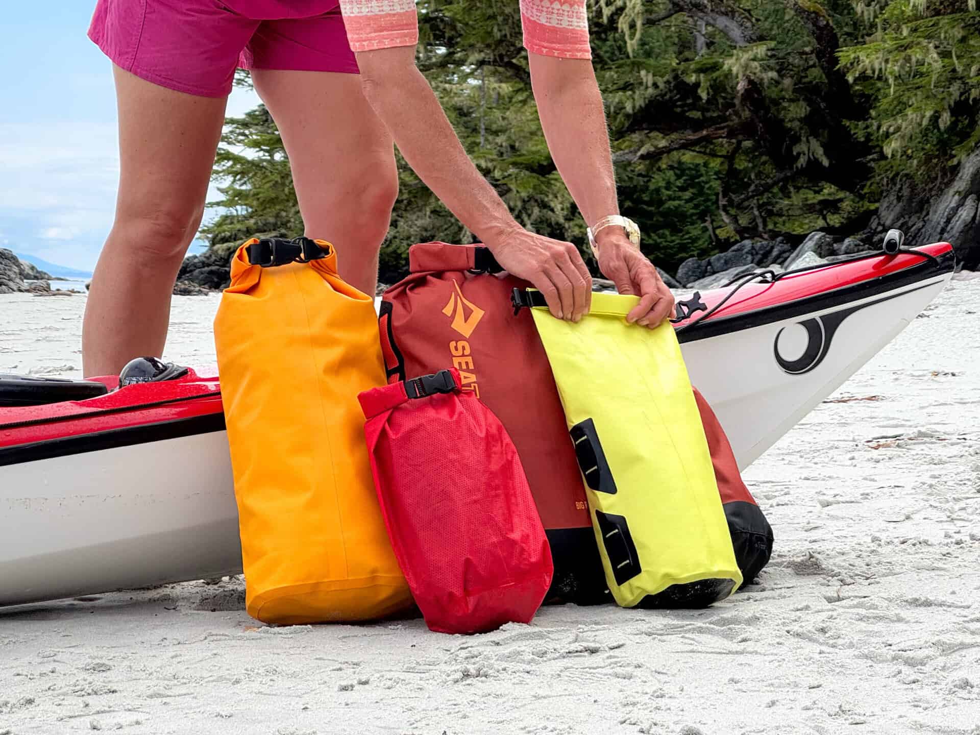 assortment of dry bags beside kayak