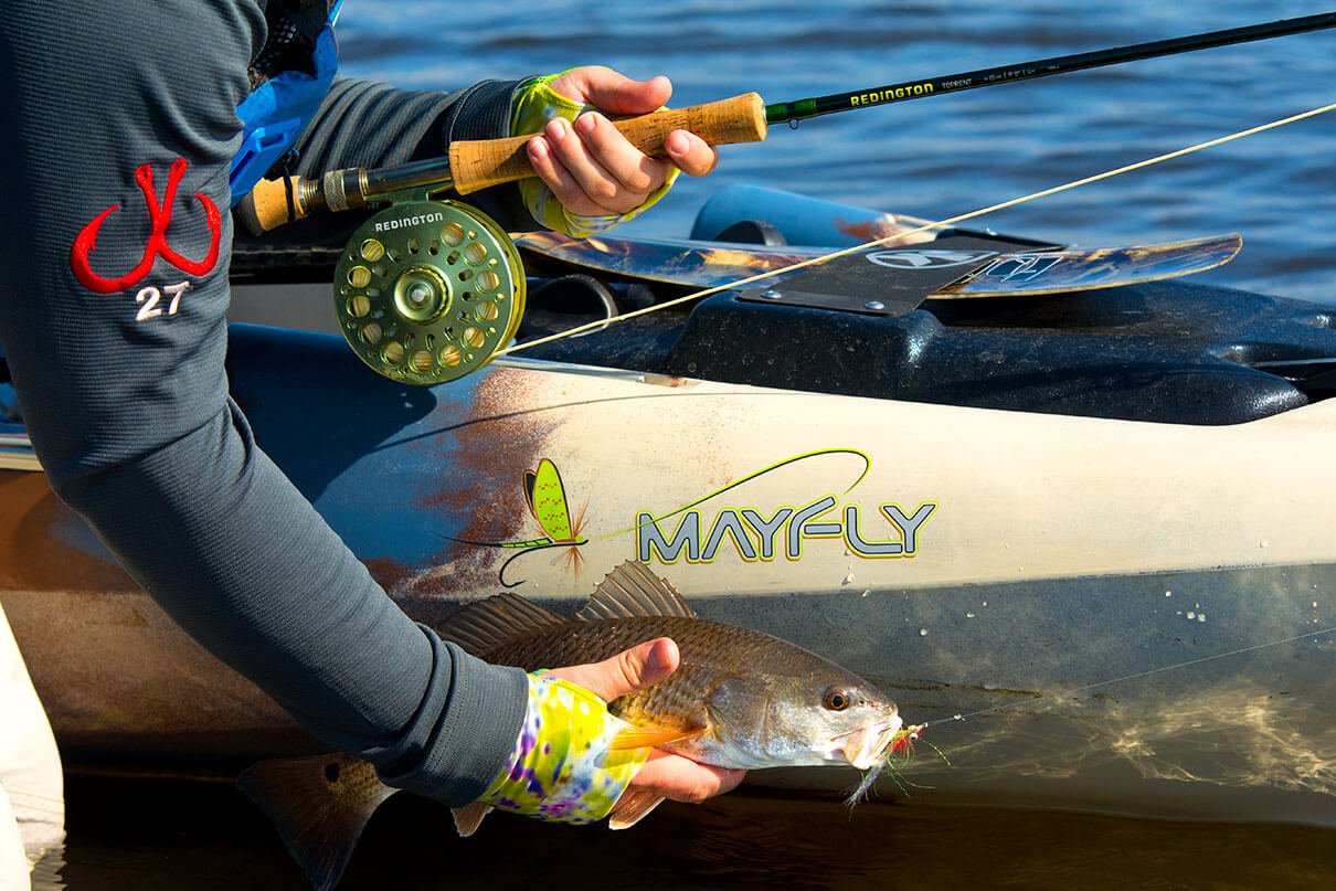 person catches a fish from a kayak