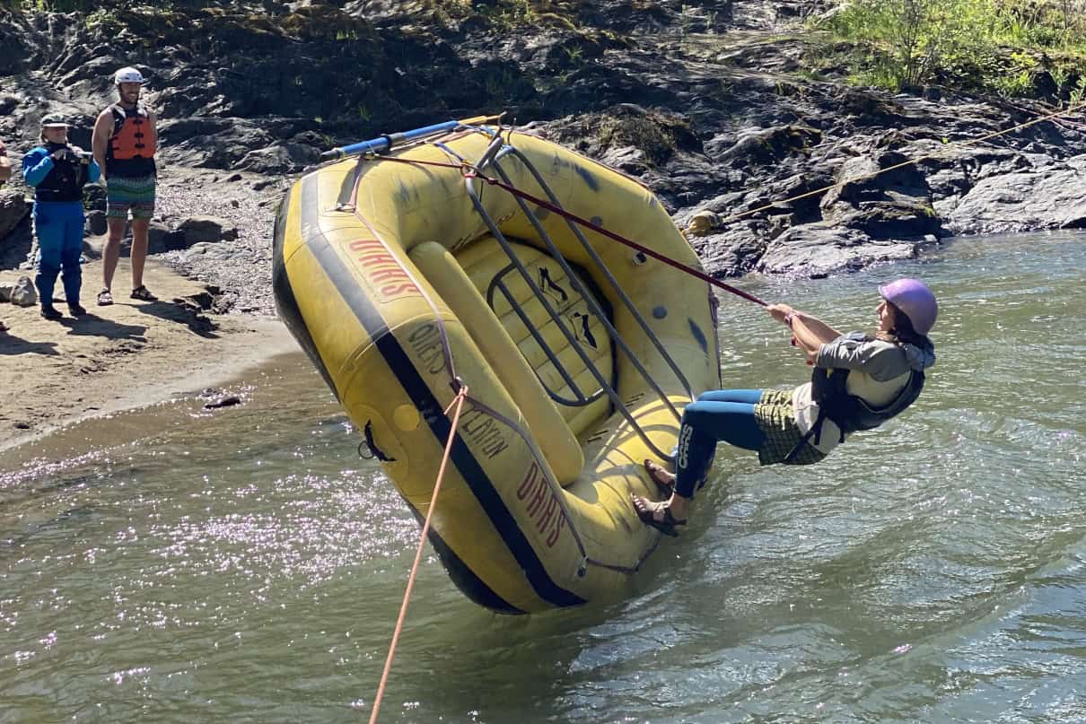 A person practices flipping a raft in flatwater.