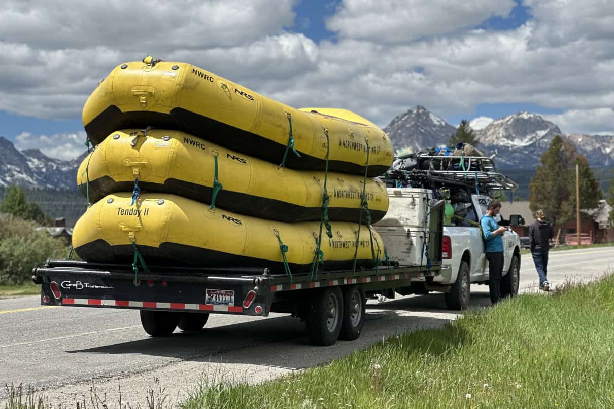 A trailer with multiple whitewater rafts stacked.