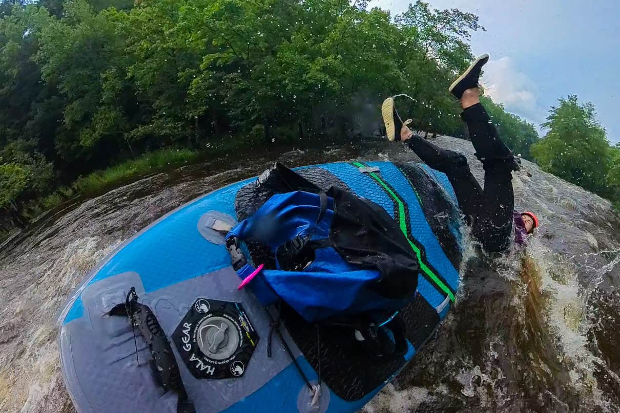 Paddler falling in water while wearing a wetsuit.