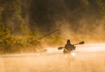 Your Gear Will Outlive You sepia toned photo of someone paddling a kayak in early morning mist