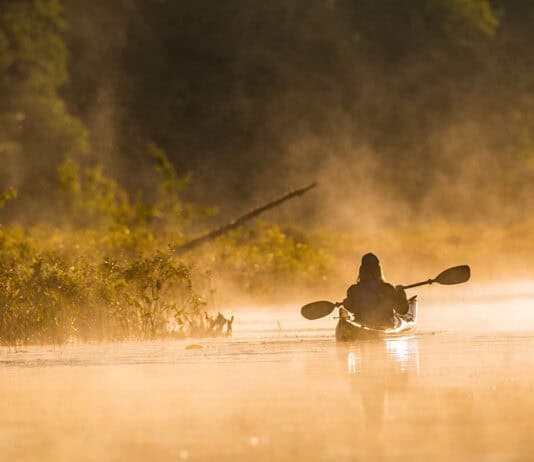 Your Gear Will Outlive You sepia toned photo of someone paddling a kayak in early morning mist
