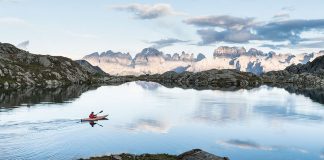 Man paddling on lake with mountains in background